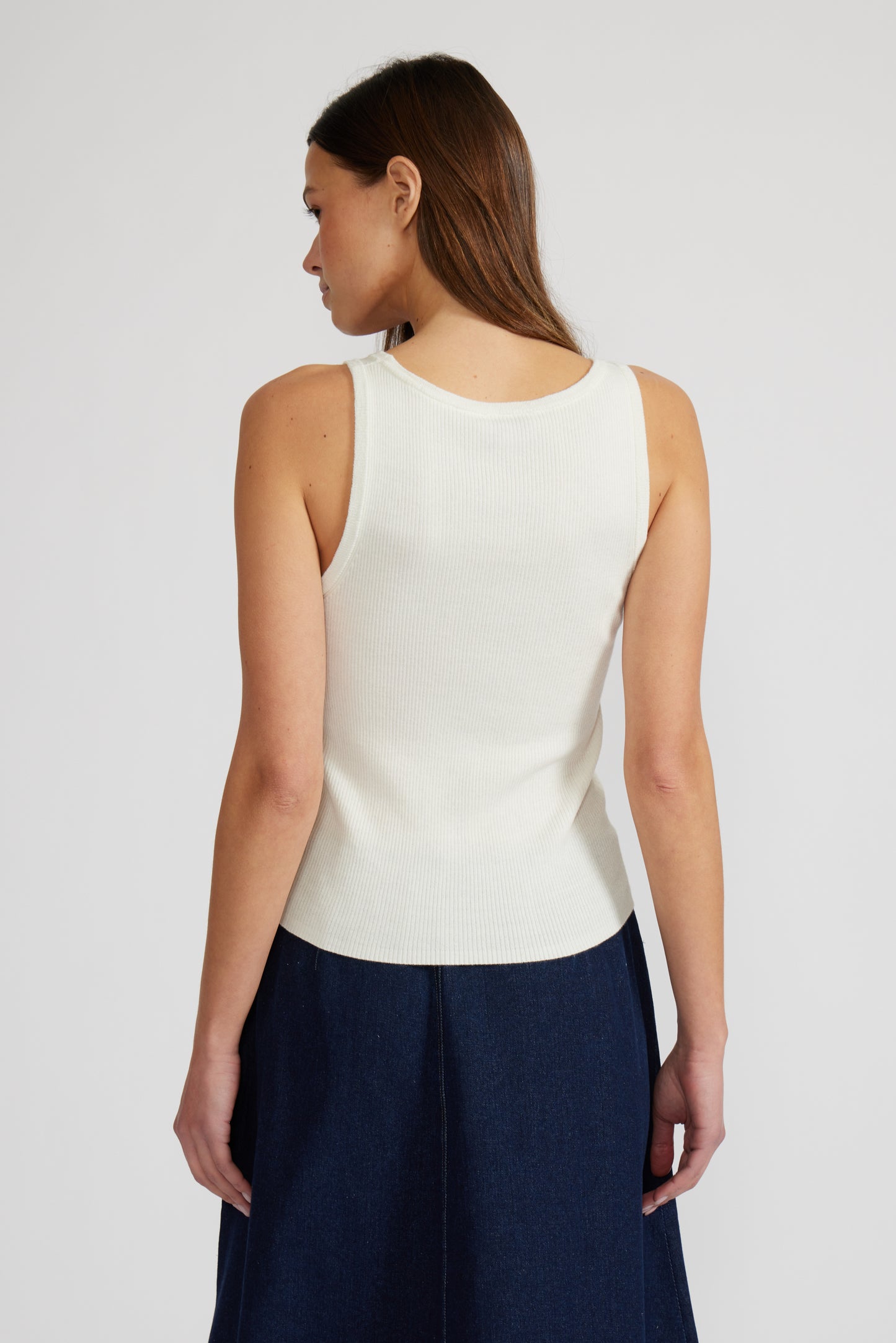 Woman wearing a white sleeveless top and navy pants on a plain background. Doreen Rhinestone Tank, a staple for curated boutique fashion and chic affordable style available at your Womens Boutique West Palm Beach, FL.