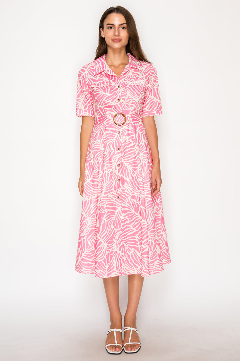 Woman wearing a pink patterned dress on a white background. Pink and white patterned dress with a belt on a plain background. West Palm Beach, Florida Womens Clothing Boutique. The Spark Boutique
