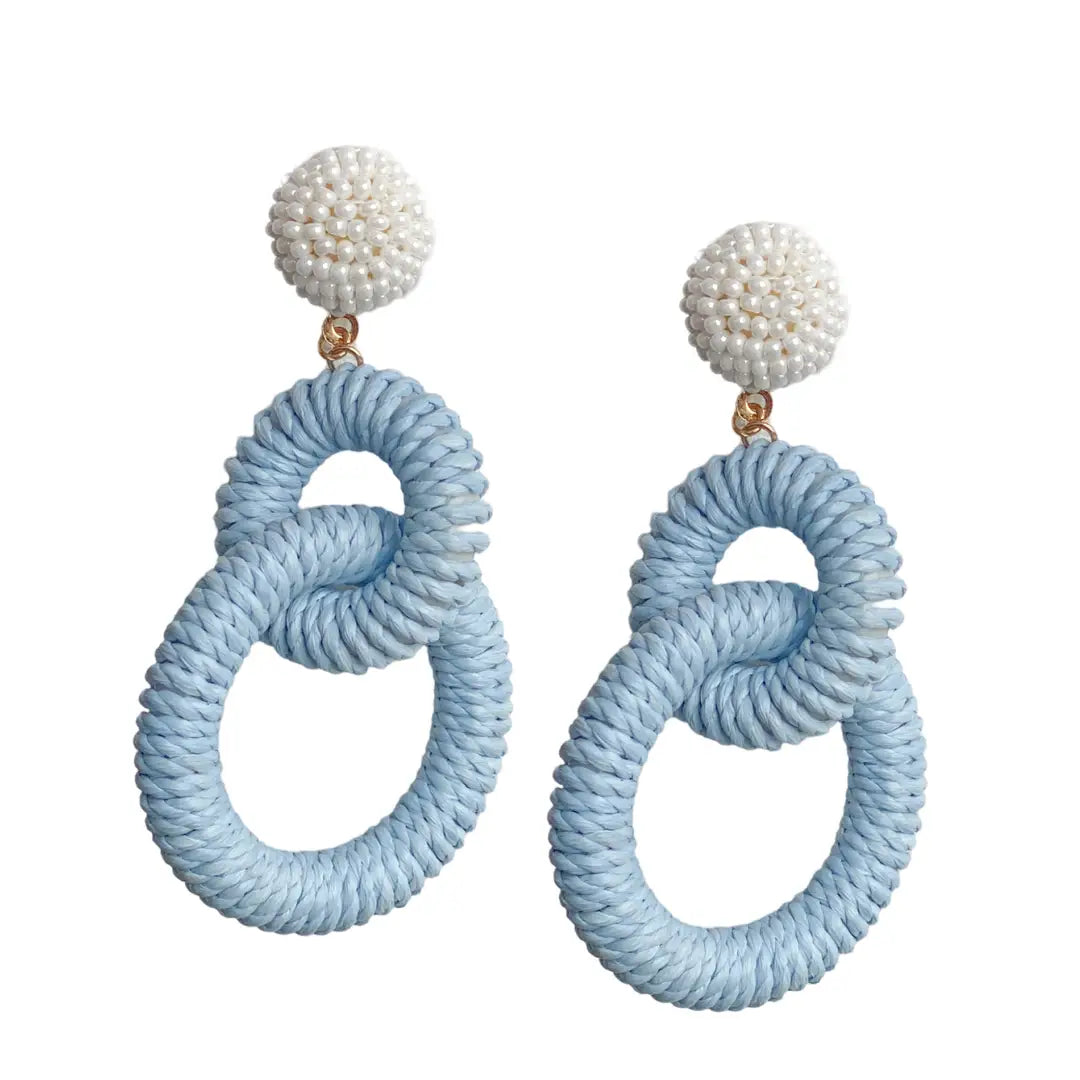 Pair of earrings with light blue circular designs and white spherical tops on a white background