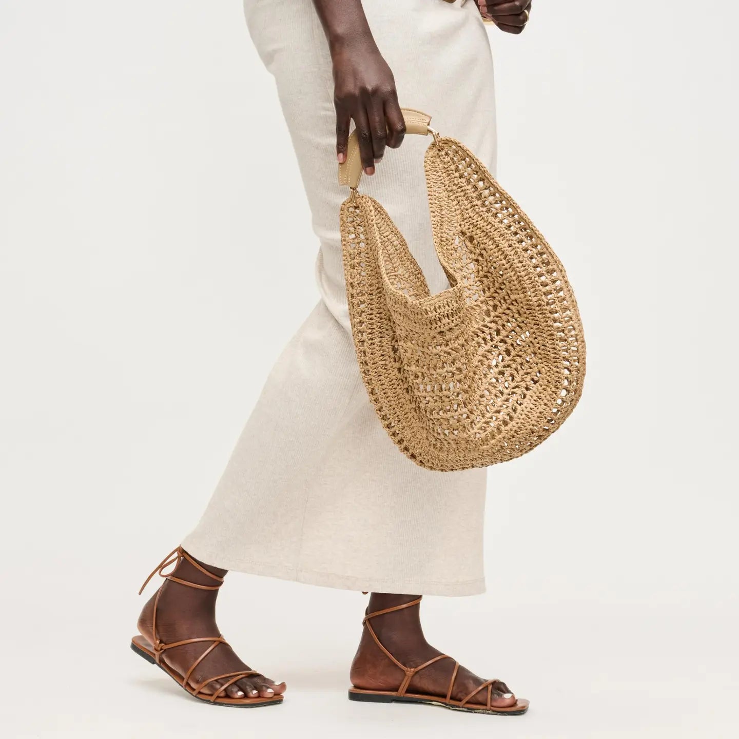 Person holding a woven straw bag with a plain background