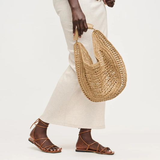 Person holding a woven straw bag with a plain background