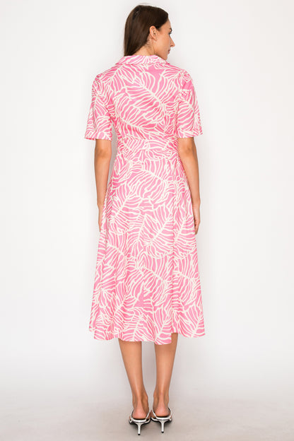 Woman wearing a pink and white patterned dress on a white background. Pink and white patterned dress with a belt on a plain background. West Palm Beach, Florida Womens Clothing Boutique. The Spark Boutique