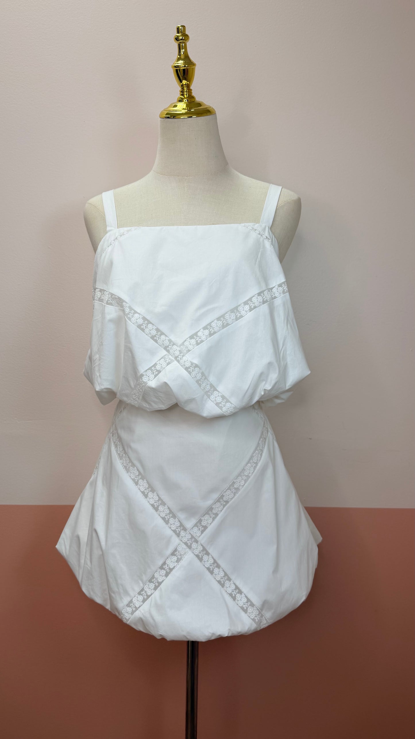 White lace top and skirt set on a mannequin against a plain background.Bubble hem crop top with delicate lace trim neckline detail. The Spark Boutique| West Palm Beach