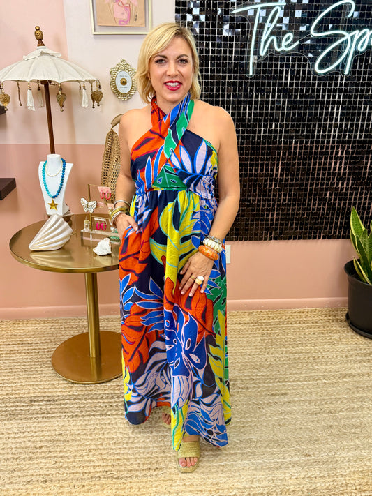 Woman in a colorful dress standing in a stylish interior setting with decor elements.