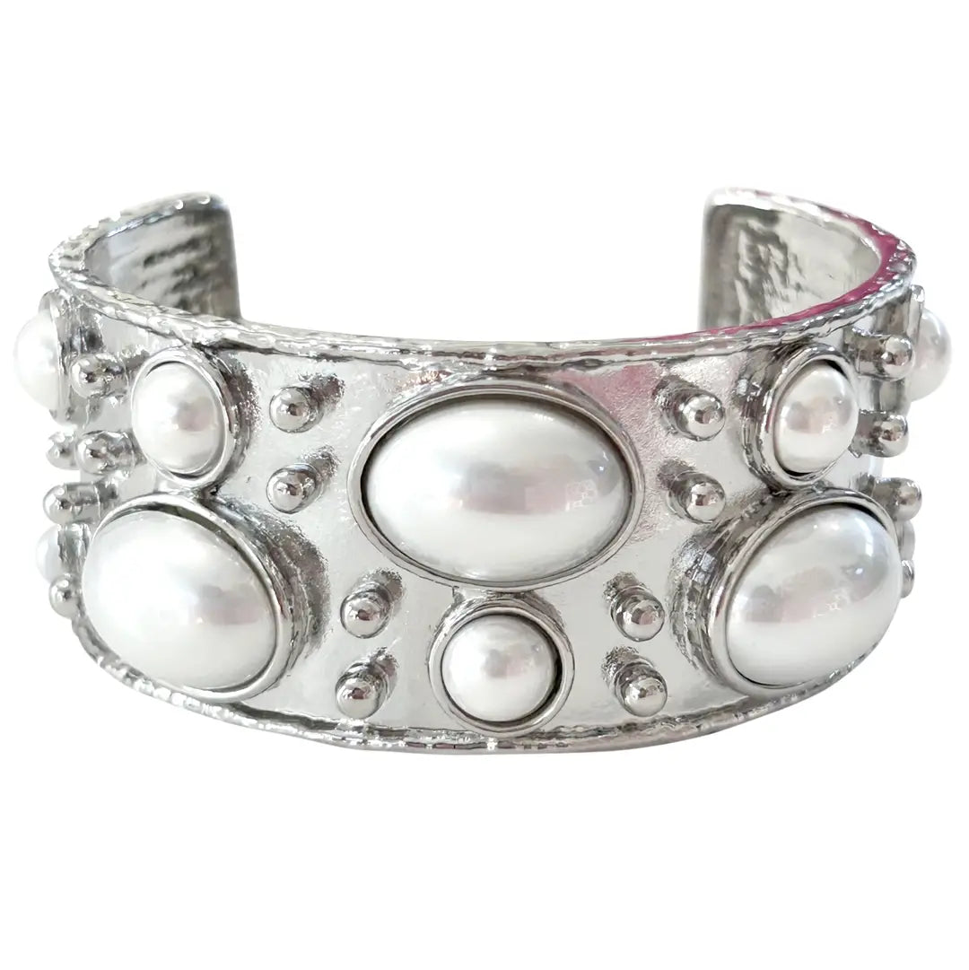 Silver cuff bracelet with embedded pearls on a white background