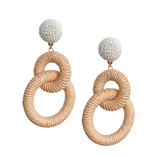 Pair of earrings with beige circular designs and white spherical tops on a white background