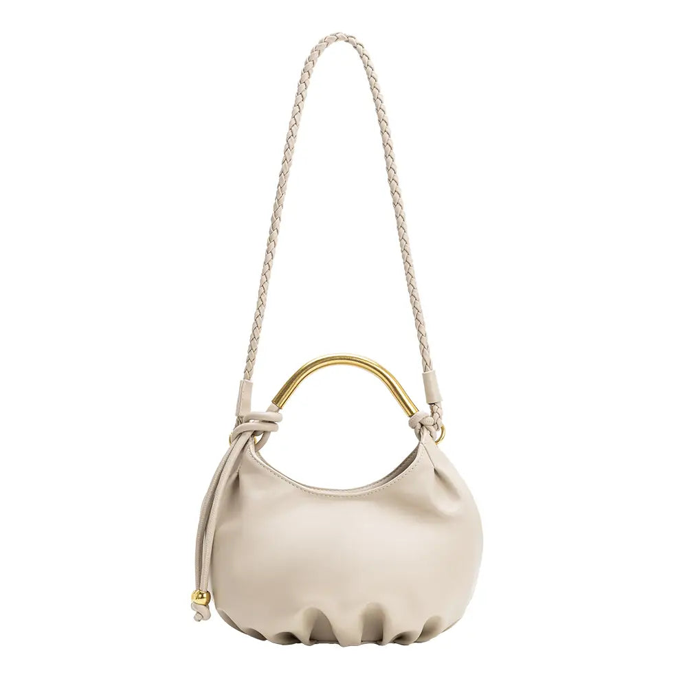 A cream-colored leather shoulder bag with a sculptural, gathered silhouette, a braided shoulder strap, and a polished gold-tone metal top handle, shown against a plain white background.